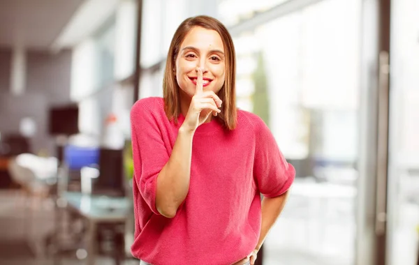 young woman full body. smiling, with index finger in front of mouth, requesting silence or sharing a secret