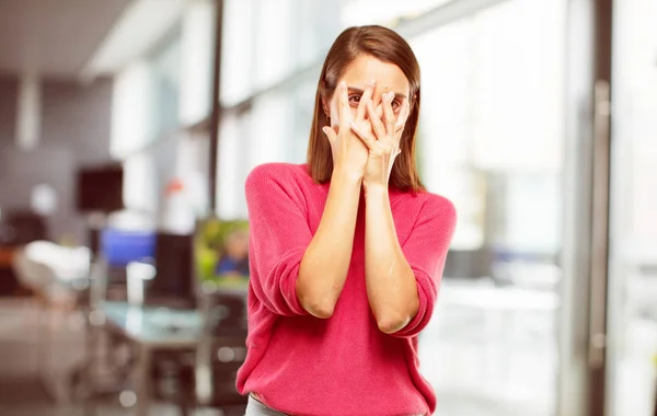 young woman full body. with a scared, frightened expression, covering eyes with both hands, peeking.