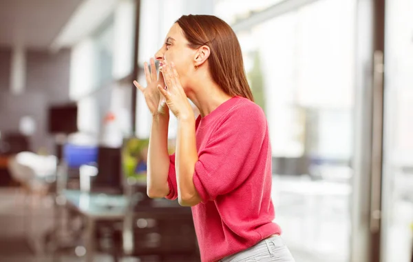 young woman full body. shouting loud like crazy, calling with hand with an angry expression, communicating a big announcement. Lateral or side view.