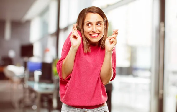 young woman full body. crossing fingers wishing for luck, with a hopeful, eager and excited expression.