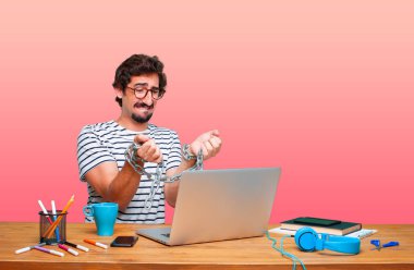 bir zincir ile bir dizüstü bilgisayar ile bir masa üzerine genç deli grafik tasarımcı. Özgürlük kavramı.