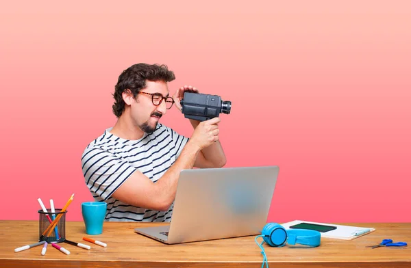 young crazy graphic designer on a desk with a laptop and with a vintage cinema camera