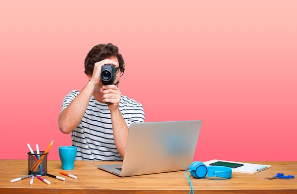young crazy graphic designer on a desk with a laptop and with a vintage cinema camera