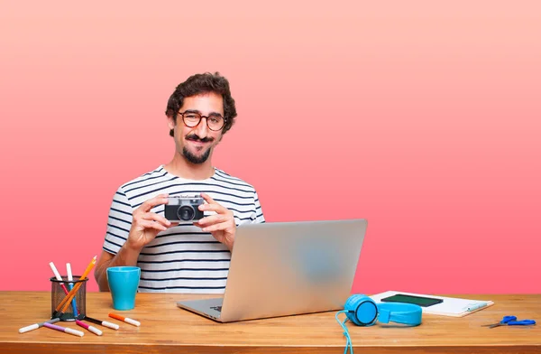 young crazy graphic designer on a desk with a laptop and with a vintage camera