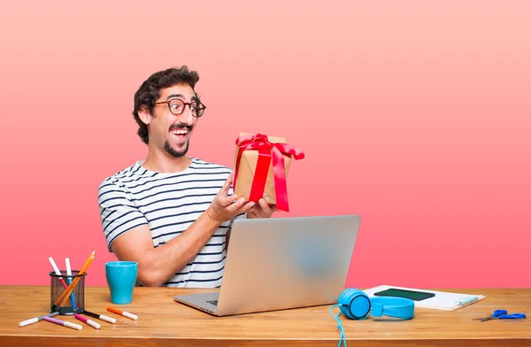 young crazy graphic designer on a desk with a laptop and with gift box concept