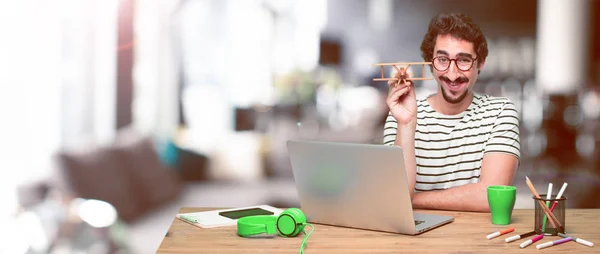 Junger Verrückter Grafiker Auf Einem Schreibtisch Mit Laptop Und Holzflugzeug — Stockfoto