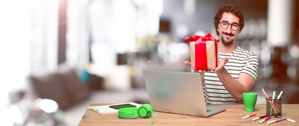 young crazy graphic designer on a desk with a laptop and with gift box concept