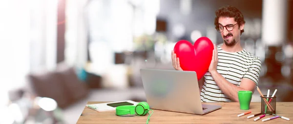 young crazy graphic designer on a desk with a laptop and with a heart shape. Love concept.