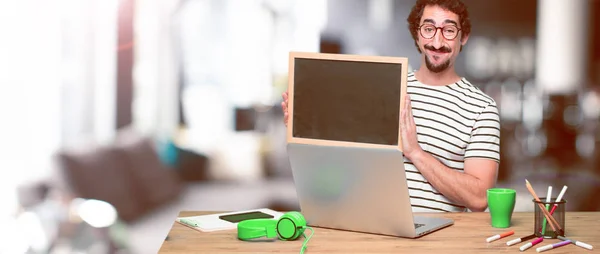 Junger Verrückter Grafiker Auf Einem Schreibtisch Mit Laptop Und Plakat — Stockfoto