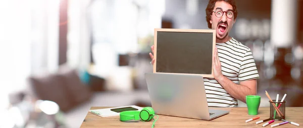 Junger Verrückter Grafiker Auf Einem Schreibtisch Mit Laptop Und Plakat — Stockfoto