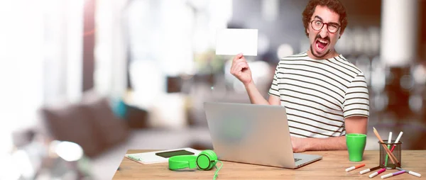 Junger Verrückter Grafiker Auf Einem Schreibtisch Mit Laptop Und Plakat — Stockfoto