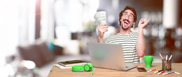 young crazy graphic designer on a desk with a laptop and pay, buying or money concept