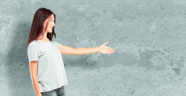 Genç güzel bir gülümseyen kız tam vücut kendinden emin, gurur, memnun ve iyi bir anlaşma kapanış bir el sıkışma sunan samimi ifade veya tebrik ve sizi karşılayan. Yanal veya yan görünüm.