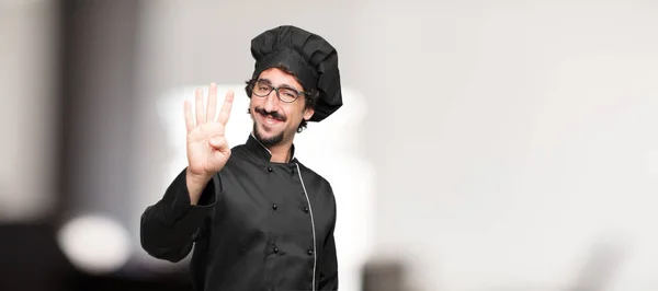 Joven Chef Sonriendo Mirando Satisfecho Feliz Contando Número Cuatro Con —  Fotos de Stock