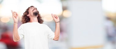 Genç hipster adam her ikisi ile gurur, memnun ve mutlu bir görünüm ile güvenle bakan bir meydan okuma sanki kalçalarına, eller. Akimbo silah geniş bir gülümseme ile poz. Öfkeli bir ifade olabilir. Geri ya da arka görünüm.