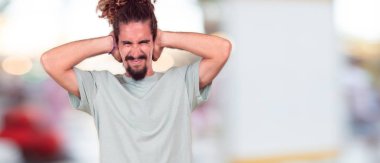 Genç hipster adam ile her ikisi gürültü rahatsız edici bir rahatsız, yüksek sesle, onları korumak için kapak kulakları eller. Yanal veya yan görünüm.