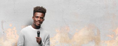 Genç siyah adam bir mikrofonla şarkı