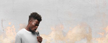 Genç siyah adam bir mikrofonla şarkı