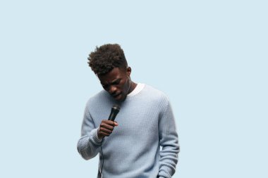 Genç siyah adam bir mikrofonla şarkı