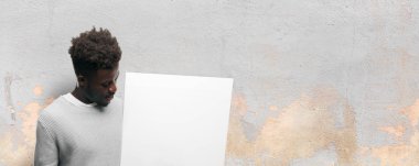 Senin konseptin yerleştirmek için boş bir afişini tutan genç siyah adam