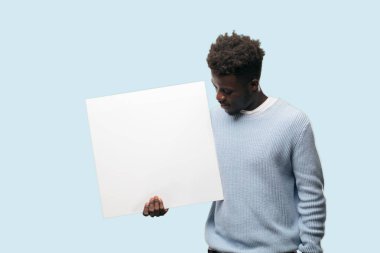 Senin konseptin yerleştirmek için boş bir afişini tutan genç siyah adam