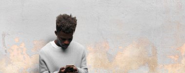 Genç siyah adam akıllı bir cep telefonu kullanarak