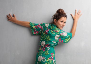 Senin konseptin yerleştirmek için çimento duvar arka plan boşluk ile poz genç güzel kadın