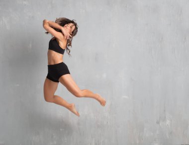 Genç güzel kadın sokak dansçısı grunge duvar arka planı atlama