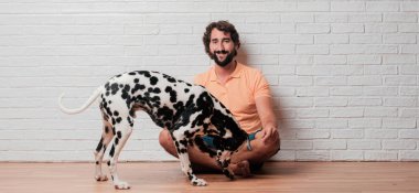 Genç sakallı adam beyaz tuğla karşı Dalmaçyalı köpekli duvar arka plan