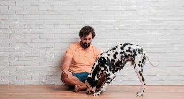 Genç sakallı adam beyaz tuğla karşı Dalmaçyalı köpekli duvar arka plan