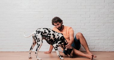 Genç sakallı adam beyaz tuğla karşı Dalmaçyalı köpekli duvar arka plan