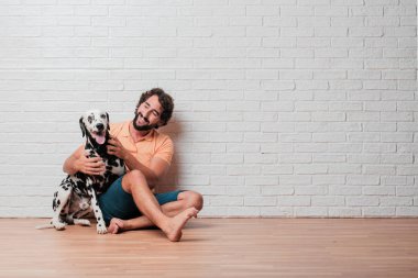 Genç sakallı adam beyaz tuğla karşı Dalmaçyalı köpekli duvar arka plan