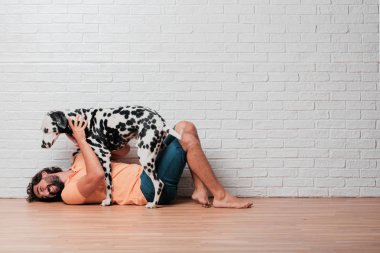 Genç sakallı adam beyaz tuğla karşı Dalmaçyalı köpekli duvar arka plan