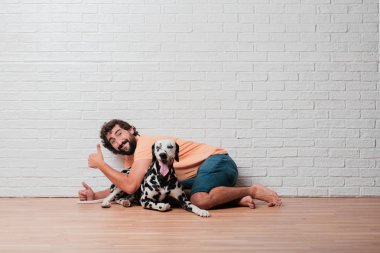 Genç sakallı adam beyaz tuğla karşı Dalmaçyalı köpekli duvar arka plan