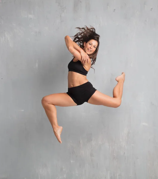 young pretty woman street dancer jumping against grunge wall background