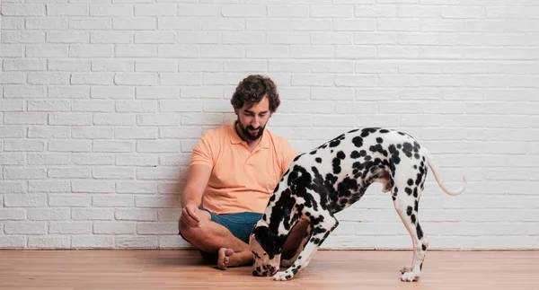Genç sakallı adam beyaz tuğla karşı Dalmaçyalı köpekli duvar arka plan