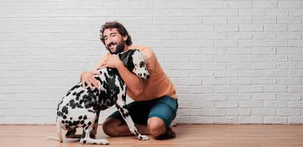 Genç sakallı adam beyaz tuğla karşı Dalmaçyalı köpekli duvar arka plan