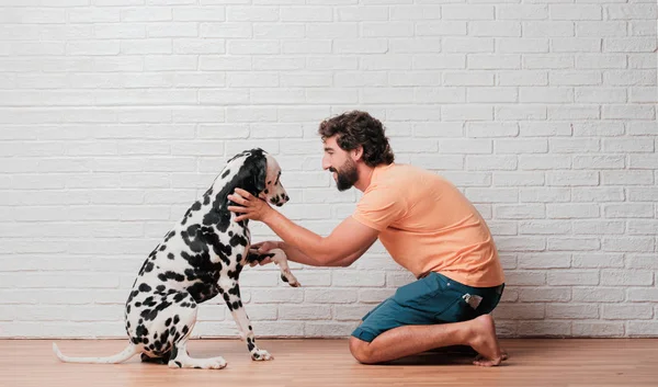 Genç sakallı adam beyaz tuğla karşı Dalmaçyalı köpekli duvar arka plan