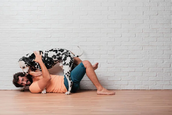 Genç sakallı adam beyaz tuğla karşı Dalmaçyalı köpekli duvar arka plan