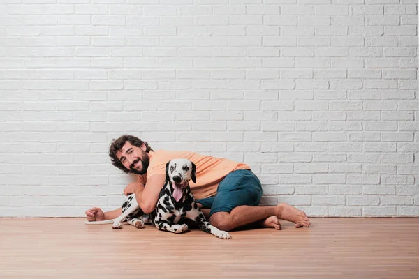 Genç sakallı adam beyaz tuğla karşı Dalmaçyalı köpekli duvar arka plan