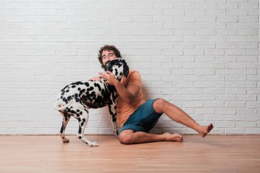 Genç sakallı adam beyaz tuğla karşı Dalmaçyalı köpekli duvar arka plan