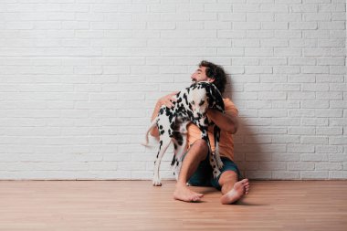 Genç sakallı adam beyaz tuğla karşı Dalmaçyalı köpekli duvar arka plan