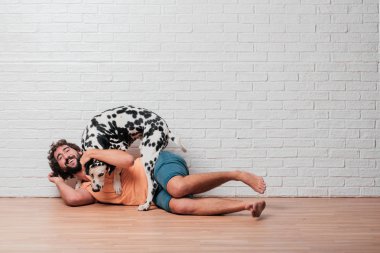 Genç sakallı adam beyaz tuğla karşı Dalmaçyalı köpekli duvar arka plan