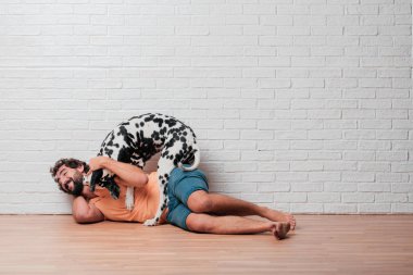 Genç sakallı adam beyaz tuğla karşı Dalmaçyalı köpekli duvar arka plan