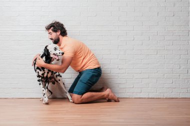 Genç sakallı adam beyaz tuğla karşı Dalmaçyalı köpekli duvar arka plan