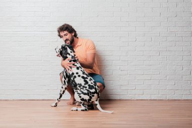 Genç sakallı adam beyaz tuğla karşı Dalmaçyalı köpekli duvar arka plan