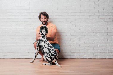 Genç sakallı adam beyaz tuğla karşı Dalmaçyalı köpekli duvar arka plan