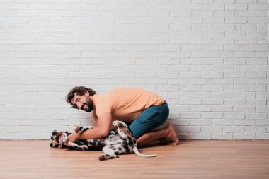 Genç sakallı adam beyaz tuğla karşı Dalmaçyalı köpekli duvar arka plan
