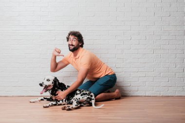 Genç sakallı adam beyaz tuğla karşı Dalmaçyalı köpekli duvar arka plan