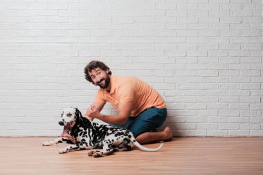 Genç sakallı adam beyaz tuğla karşı Dalmaçyalı köpekli duvar arka plan